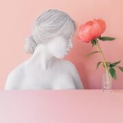 pink flower in vase near female bust