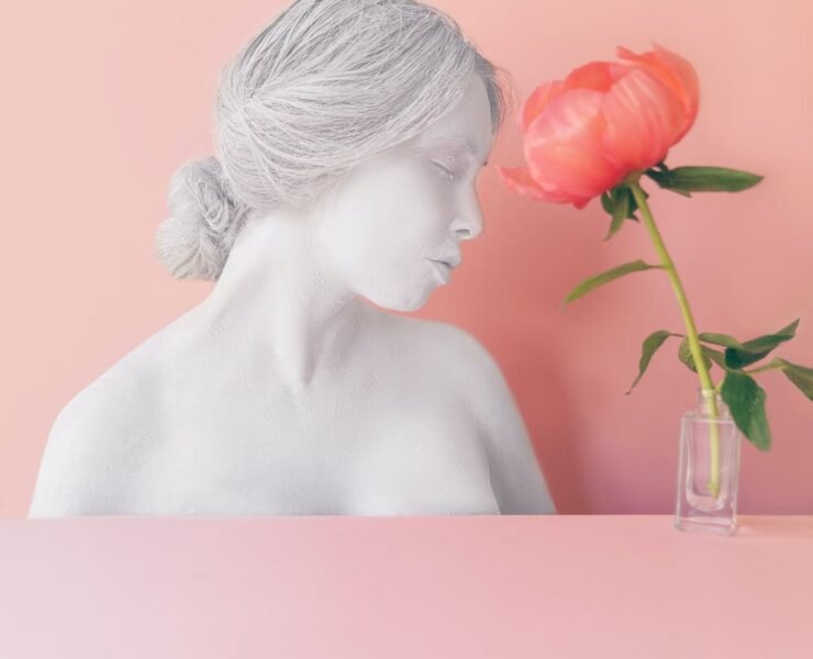 pink flower in vase near female bust