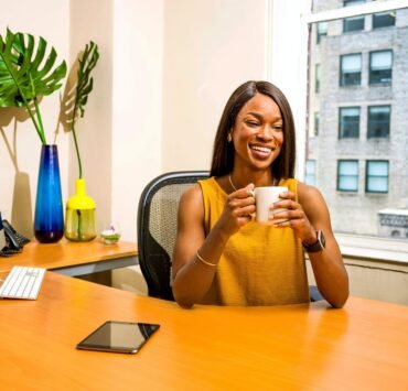 woman holding white ceramic mug at desk