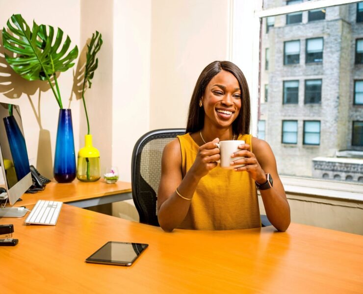 woman holding white ceramic mug at desk