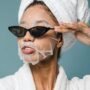 content young black woman wearing sunglasses during skin care treatment after bath